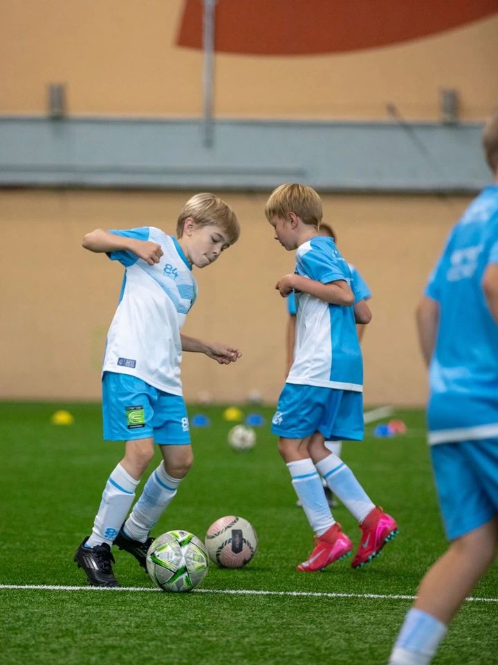 Divi zēni Coerver formās trenē bumbas vadīšanu